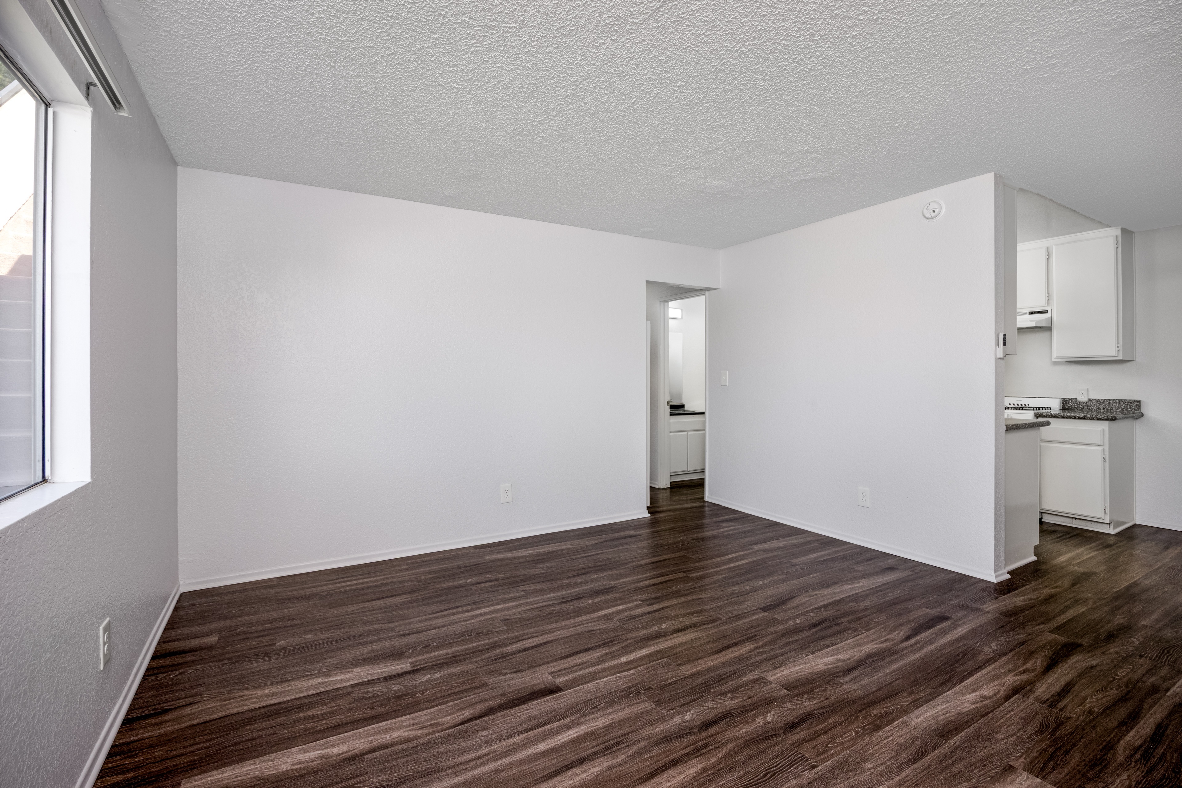 A room with wooden flooring and white walls.
